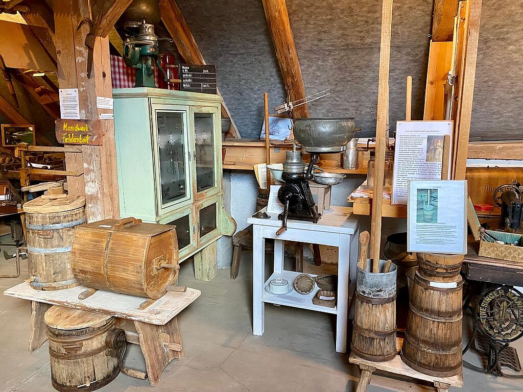 Ein alter Raum mit vielen antiken Gegenständen, vor allem alten Butterfässer